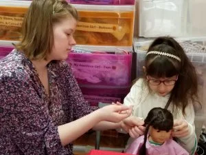 Melanie helping girl with doll hair